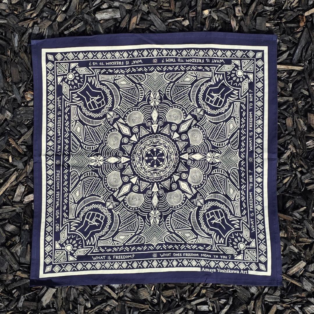 Large midnight blue bandana with white offsets shows festival logo with words of love, curiosity, freedom at the center and the questions What is Freedom, What is freedom to him, to her, to them on the borders.